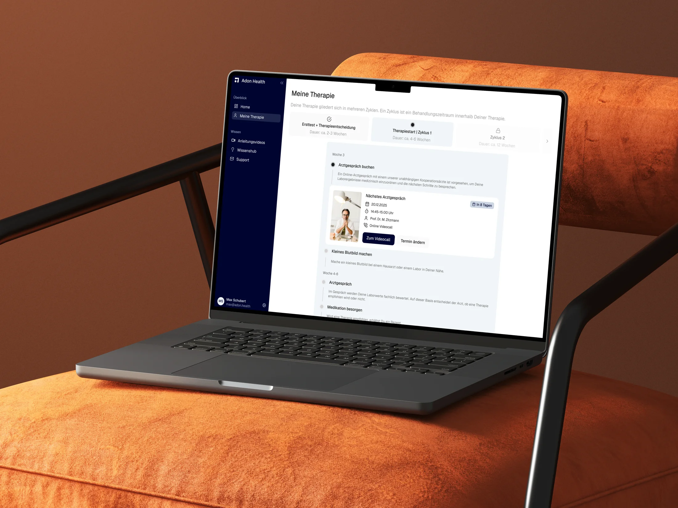 The Adon Health therapy journey displayed on a laptop resting on an orange upholstered chair
